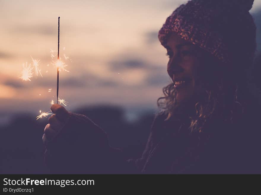 Cheerful caucasian woman with winter hat celebrate outdoor with fire sparkler - new year eve and event- happiness for alternative