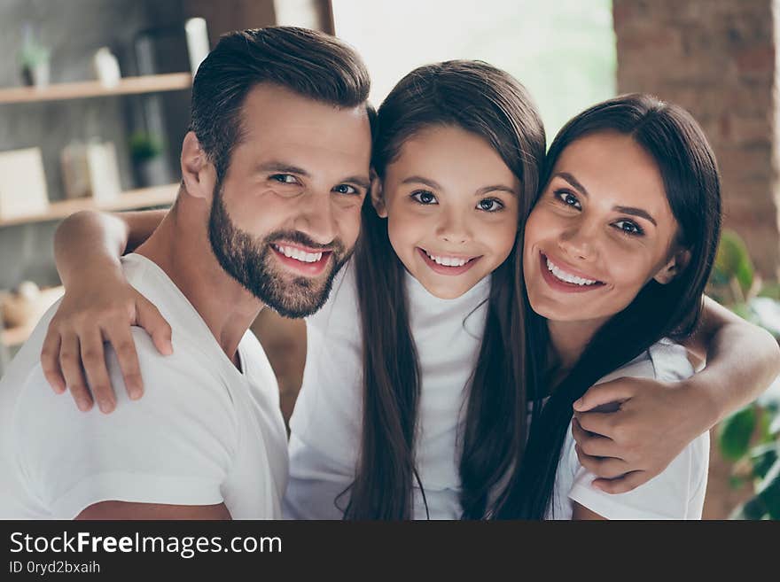 Close-up portrait of nice attractive lovely adorable affectionate gentle careful cheerful, cheery family wearing casual white t-shirts cuddling at industrial loft style interior room house. Close-up portrait of nice attractive lovely adorable affectionate gentle careful cheerful, cheery family wearing casual white t-shirts cuddling at industrial loft style interior room house