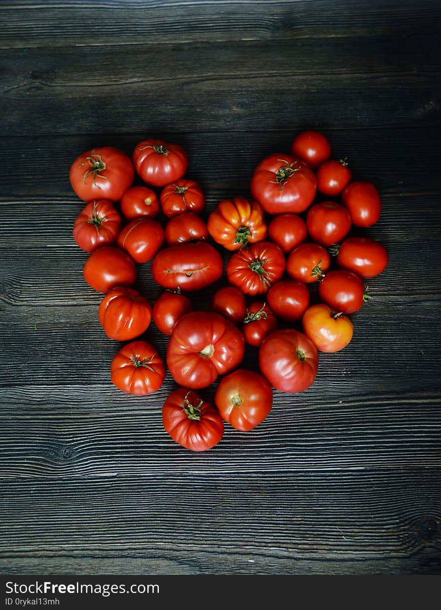 Tomatoes on the old table. Tomatoes heart. Top view of fresh vegetable on a dark wooden background. Red Food background. Horizontal composition isolated on a old rustic wooden surface. Tomatoes on the old table. Tomatoes heart. Top view of fresh vegetable on a dark wooden background. Red Food background. Horizontal composition isolated on a old rustic wooden surface