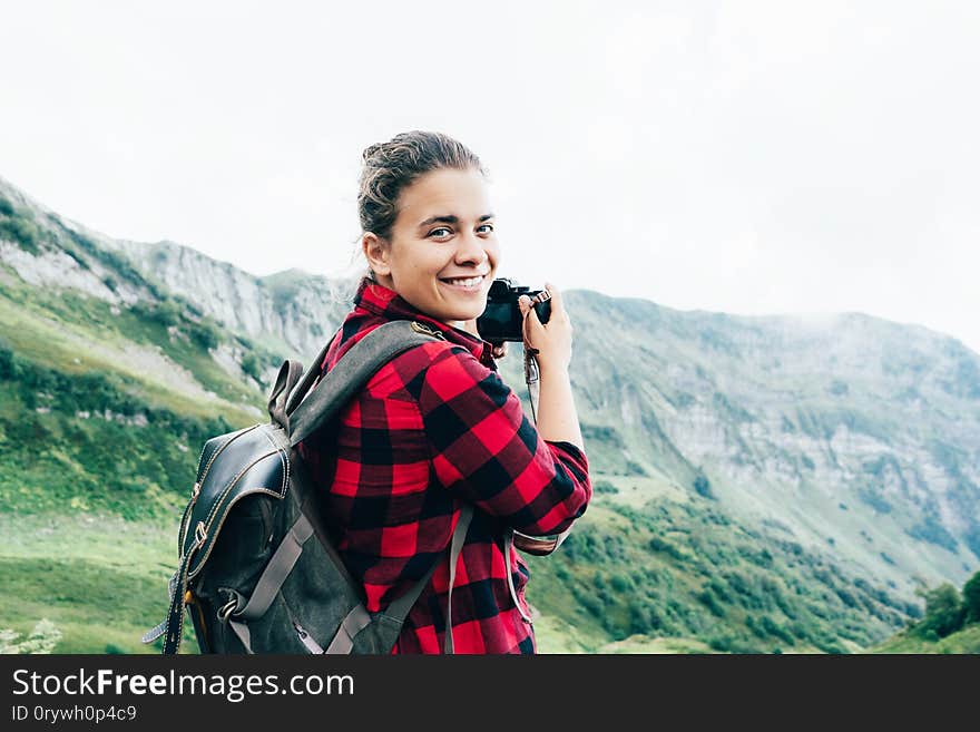 Portrait of a beautiful caucasian female photographer holding a camera in the mountains. Girl blogger makes a photo for his online blog. Journalistic content professional at work. Epic landscape. Portrait of a beautiful caucasian female photographer holding a camera in the mountains. Girl blogger makes a photo for his online blog. Journalistic content professional at work. Epic landscape.