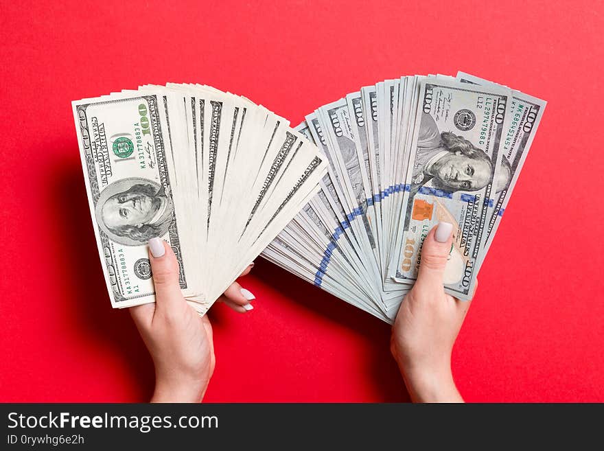 Fan of new one hundred dollar bills in one female hand and old one hundred dollar bills in another hand on colorful background. Investment concept.