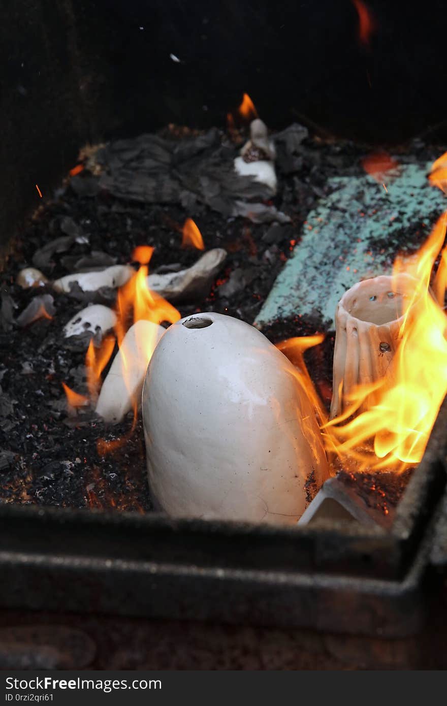 L&#x27;Art du feu. On confie aux flammes, alimentées par du papier-journal et des copeaux de bois, le soin de finaliser la cuisson. Au sortir de la boite en fer, les émaux des pièces prendront ces reflets irisés, noirs, argentés, craquelés, si caractéristiques de la technique du raku. L&#x27;Art du feu. On confie aux flammes, alimentées par du papier-journal et des copeaux de bois, le soin de finaliser la cuisson. Au sortir de la boite en fer, les émaux des pièces prendront ces reflets irisés, noirs, argentés, craquelés, si caractéristiques de la technique du raku.