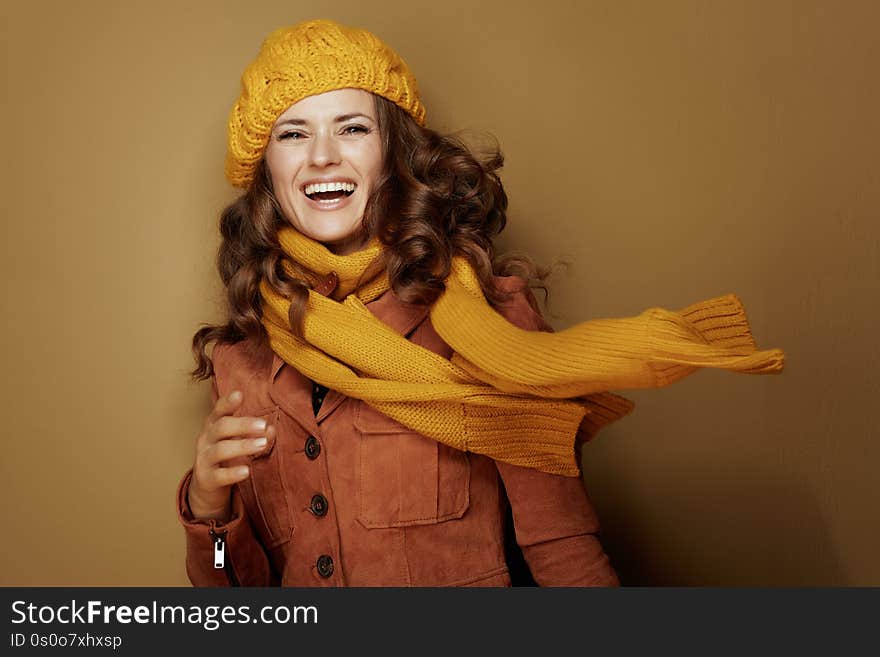 Hello autumn. Portrait of smiling trendy woman in yellow beret and scarf on bronze background. Hello autumn. Portrait of smiling trendy woman in yellow beret and scarf on bronze background