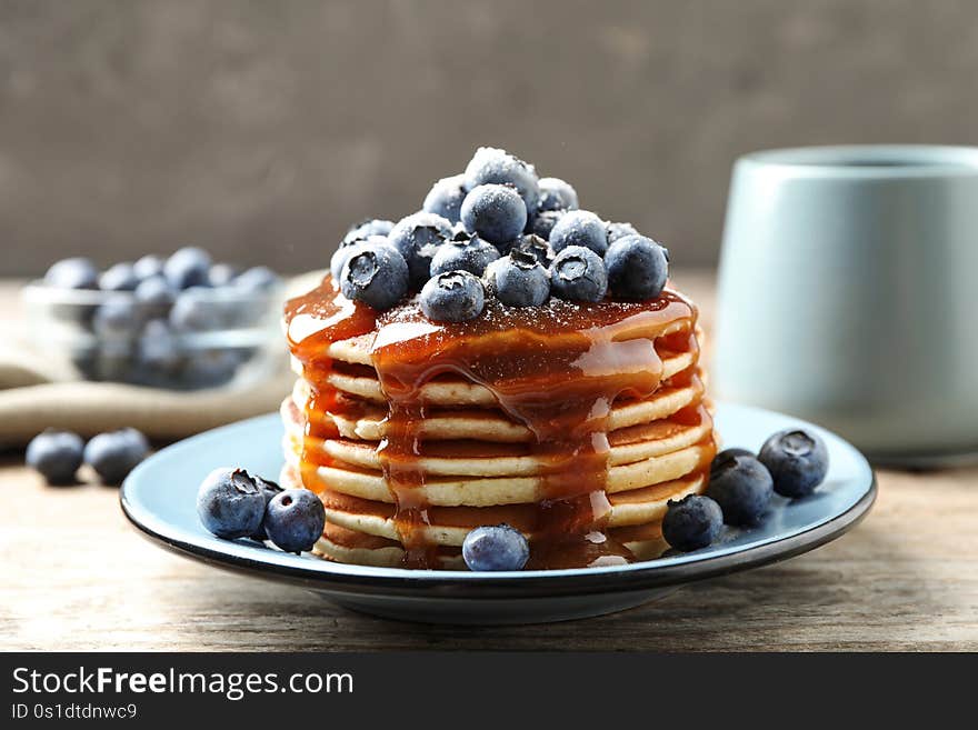 Delicious pancakes with fresh blueberries and syrup on wooden table. Delicious pancakes with fresh blueberries and syrup on wooden table