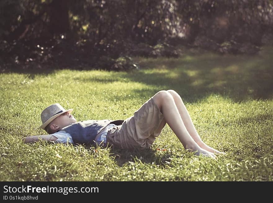 Kid in hat  lying on green grass in the park. Kid in hat  lying on green grass in the park