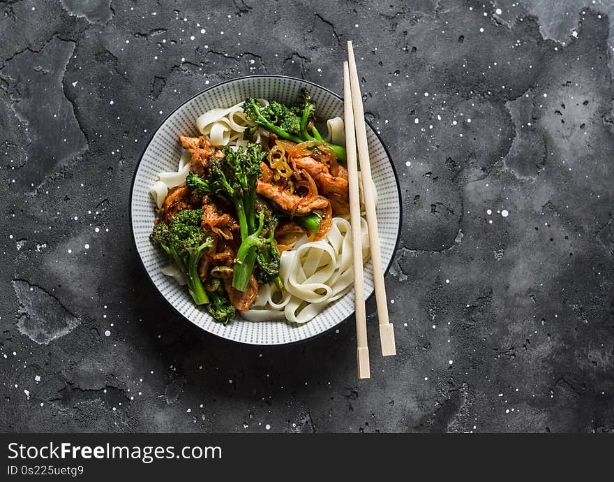 Teriyaki stir fry chicken with broccoli and noodles on dark background, top view. Asian style food