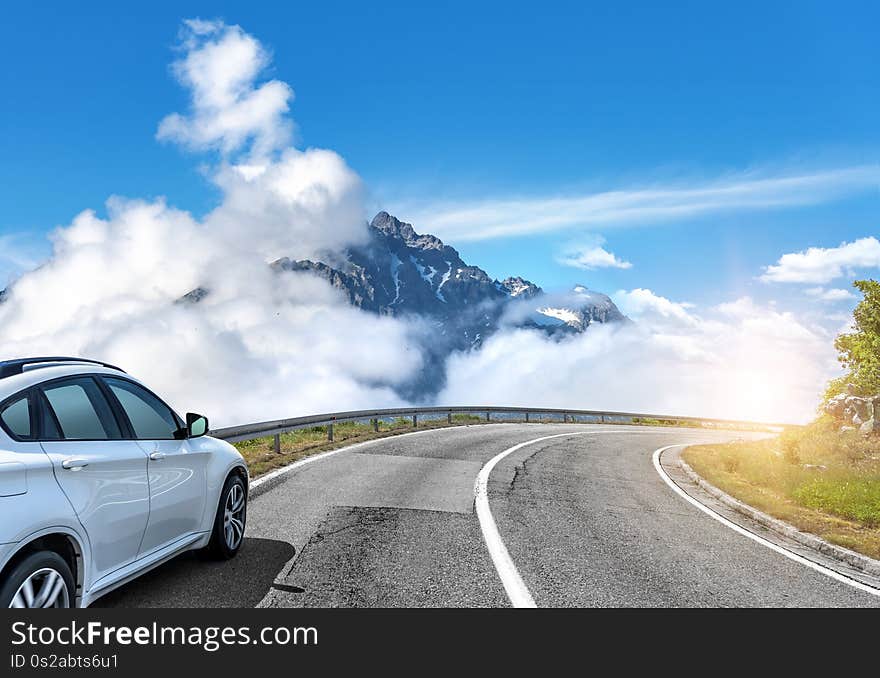 White car moves on the road among the mountains and forests.