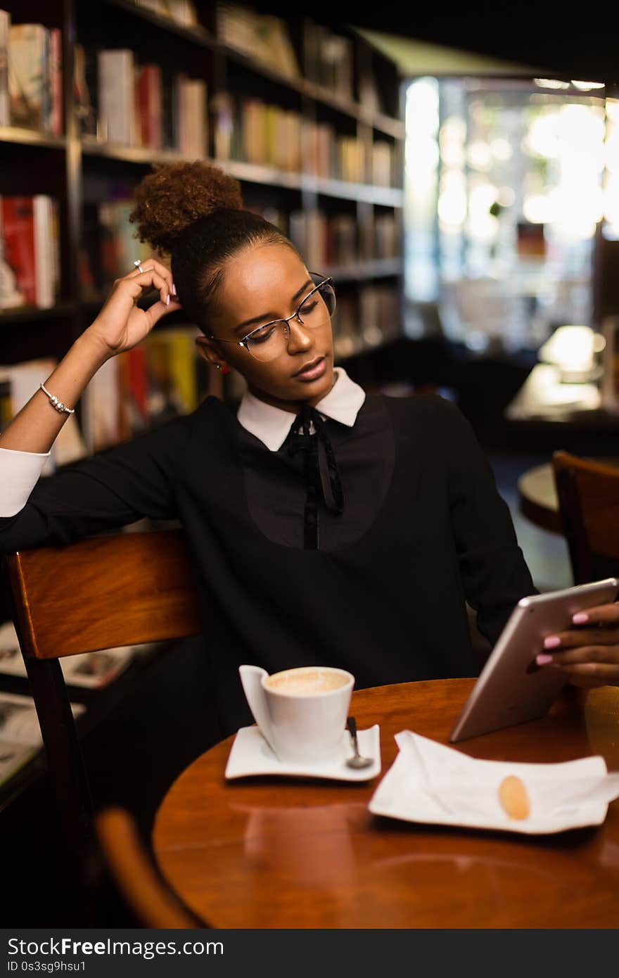 Black african american young yoman drinking coffee and using a tablet