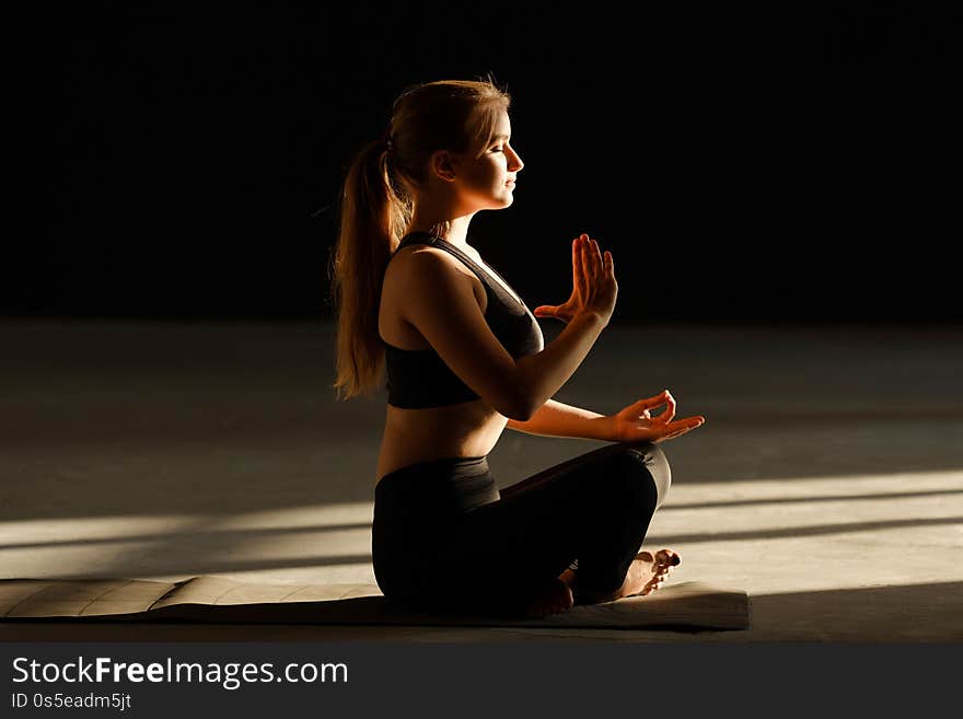 Sporty young girl is meditating alone. Girl doing yoga in the lotus position indoors, holding hands in the mudra, the concept of freedom and tranquility, close-up