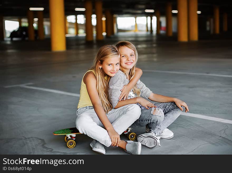 Two beautiful girls skateboarding, having fun and playing in the parking lot