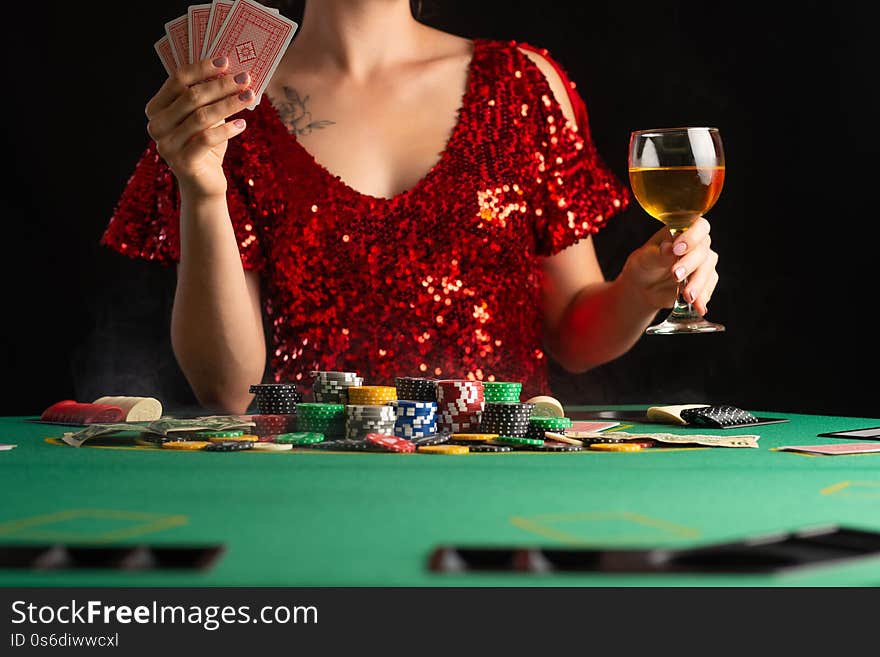 Girl in evening dress plays poker in a casino. focus on the card and focus