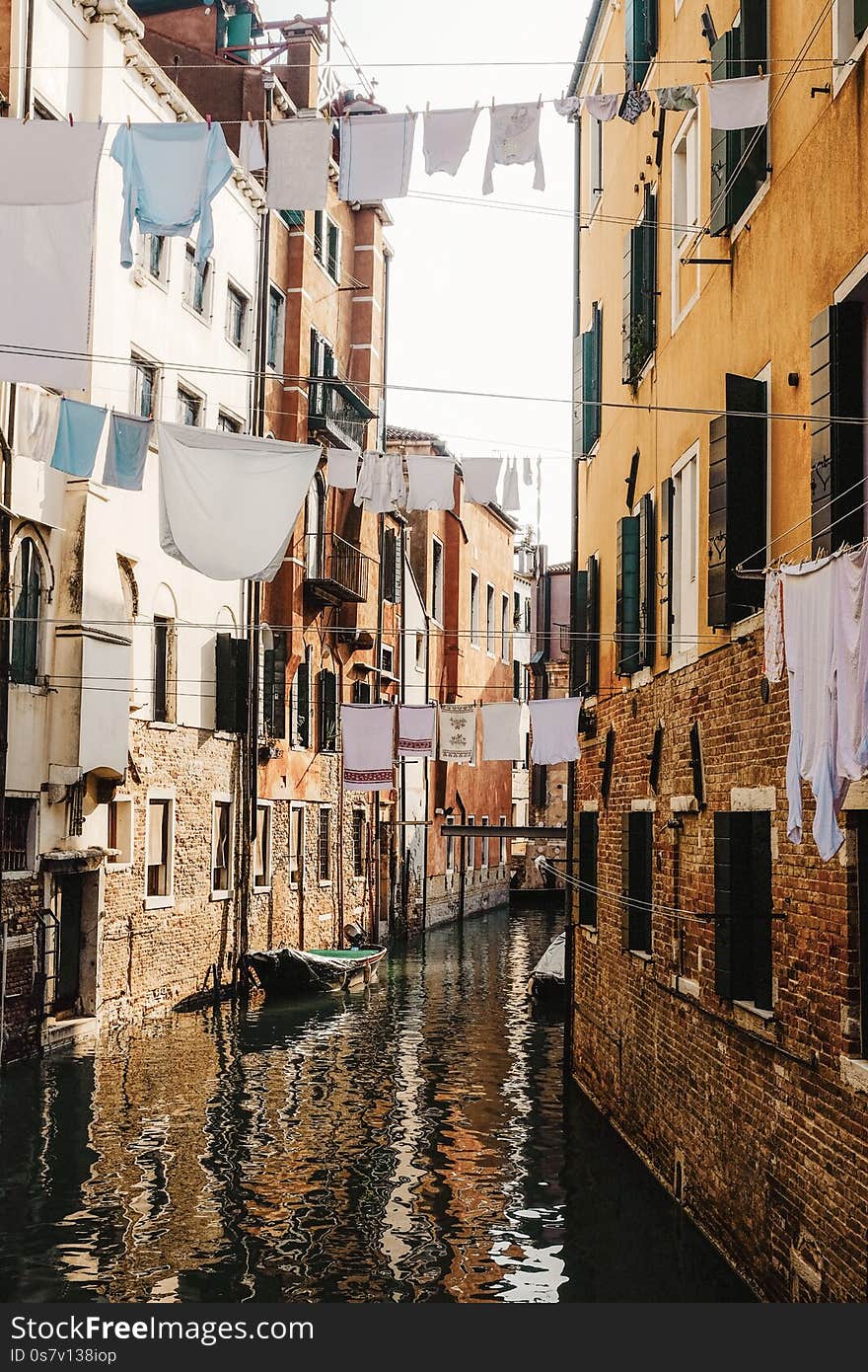 Vertical shot of clothes hanging on a cable between the concrete houses over the river in Venice