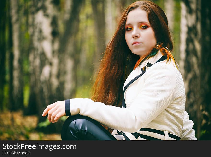 Beautiful woman with long hair and bright makeup in the autumn park