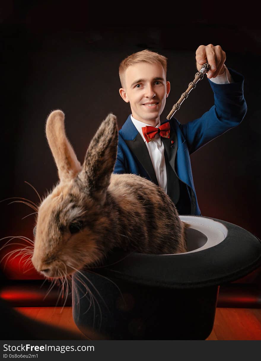 A young guy magician illusionist holding a hat with a rabbit