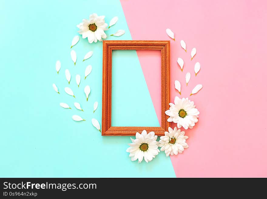 White chrysanthemum with wooden photo frame on a mint and pink background. Flat lay, top view, copy space. White chrysanthemum with wooden photo frame on a mint and pink background. Flat lay, top view, copy space