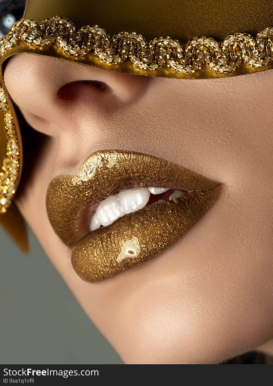 Close up view of beautiful woman lips with golden metallic lipstick. Fashion make up. Cosmetology, drugstore or fashion makeup concept. Studio shot