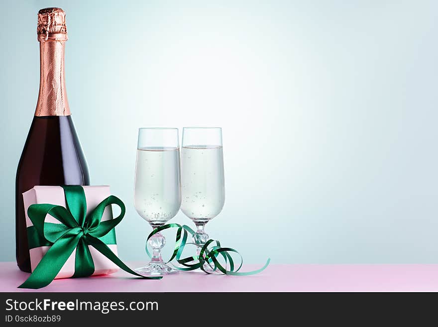 Two glasses of sparkling wine, champagne bottle and gift box in green and mint colors, copy space