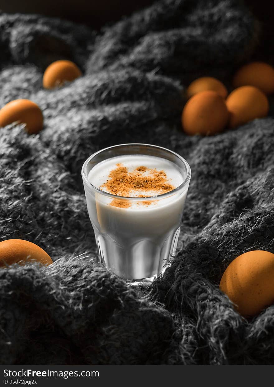 Eggnog. Traditional Christmas drink made from raw chicken eggs and milk with cinnamon in glass.