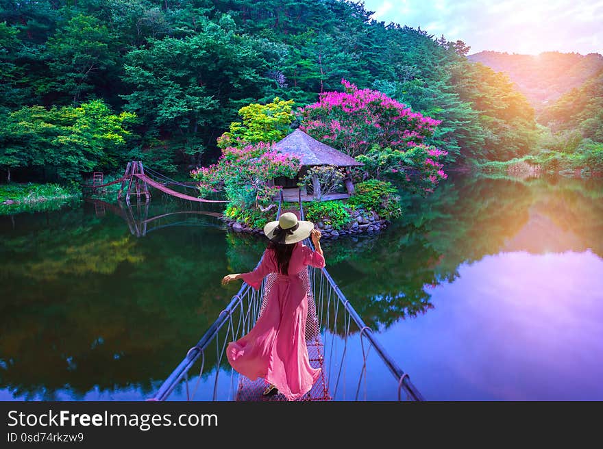 Asian woman walks on a red bridge to an island resort in Suncheon, South Korea.
