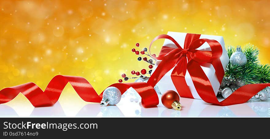 Christmas gift with decoration on yellow bokeh background. Holiday greeting card