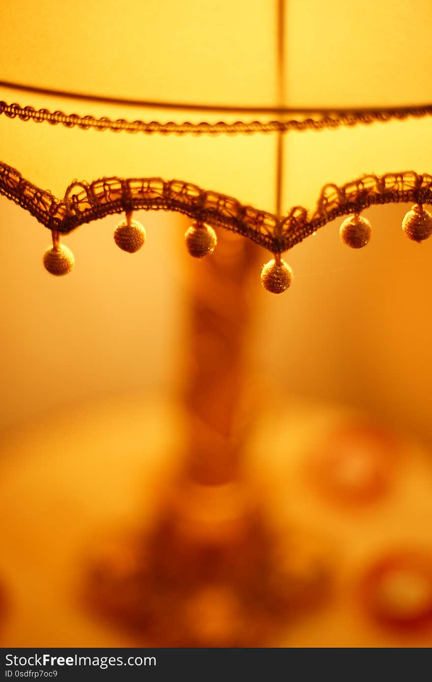 Fabric lampshade with golden balls and warm light. Close-up, selective focus