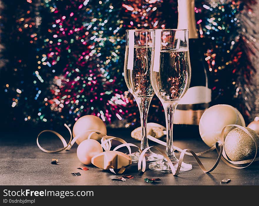 Champagne in glass goblets a bottle of Christmas toys Serpentine stars sparkling festive background. New year concept.