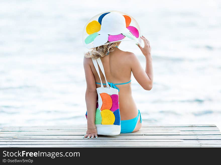 The girl is sitting on a bench by the sea