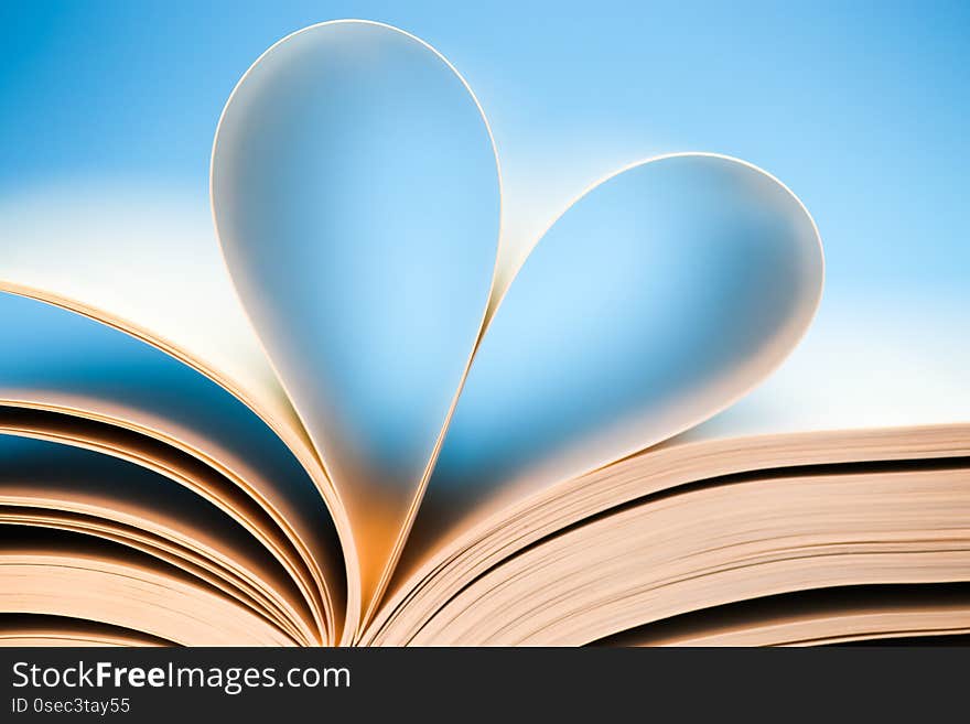 Book pages on blue background, glowing heart formed by book