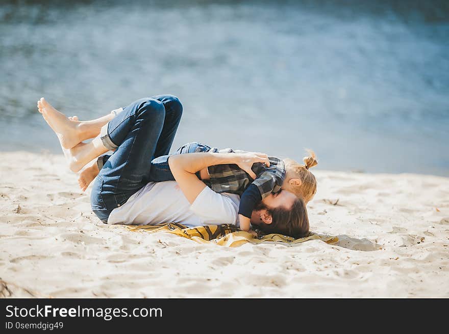 A happy father playing with young son at the sandy beach. Side view