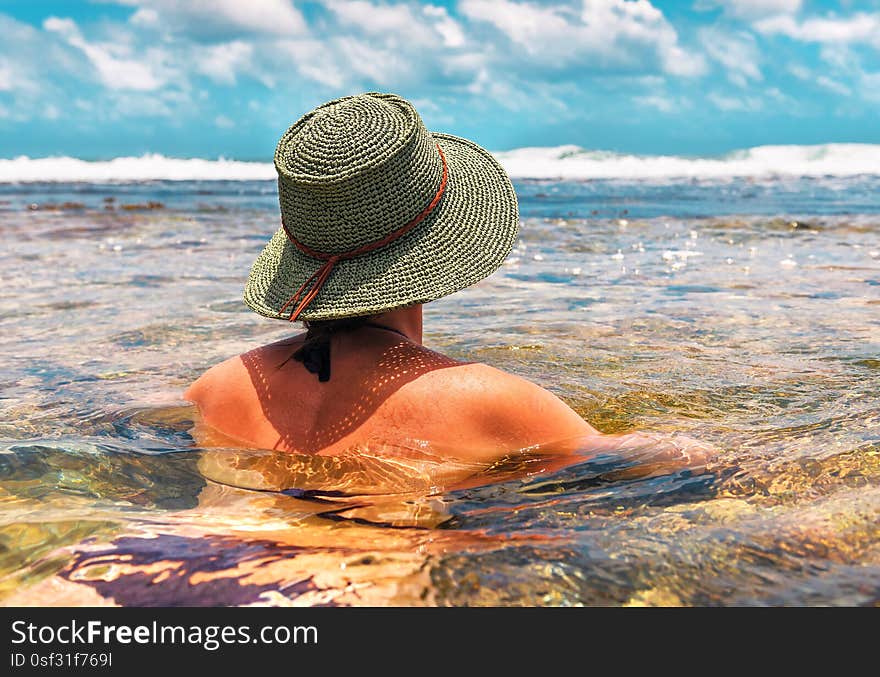 Girl in a green knitted hat floats in the ocean