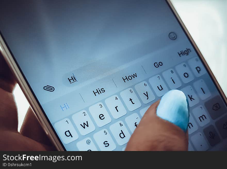 Female hand with blue nails is typing on a white smartphone a message.