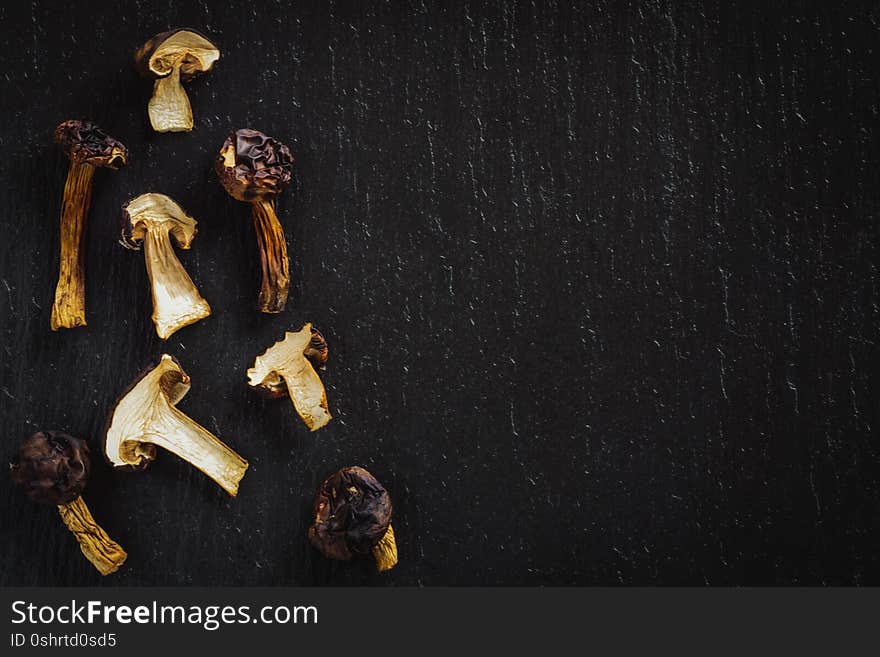 Dried slices of tasty mushrooms on black stone background.  Top view cooking theme.