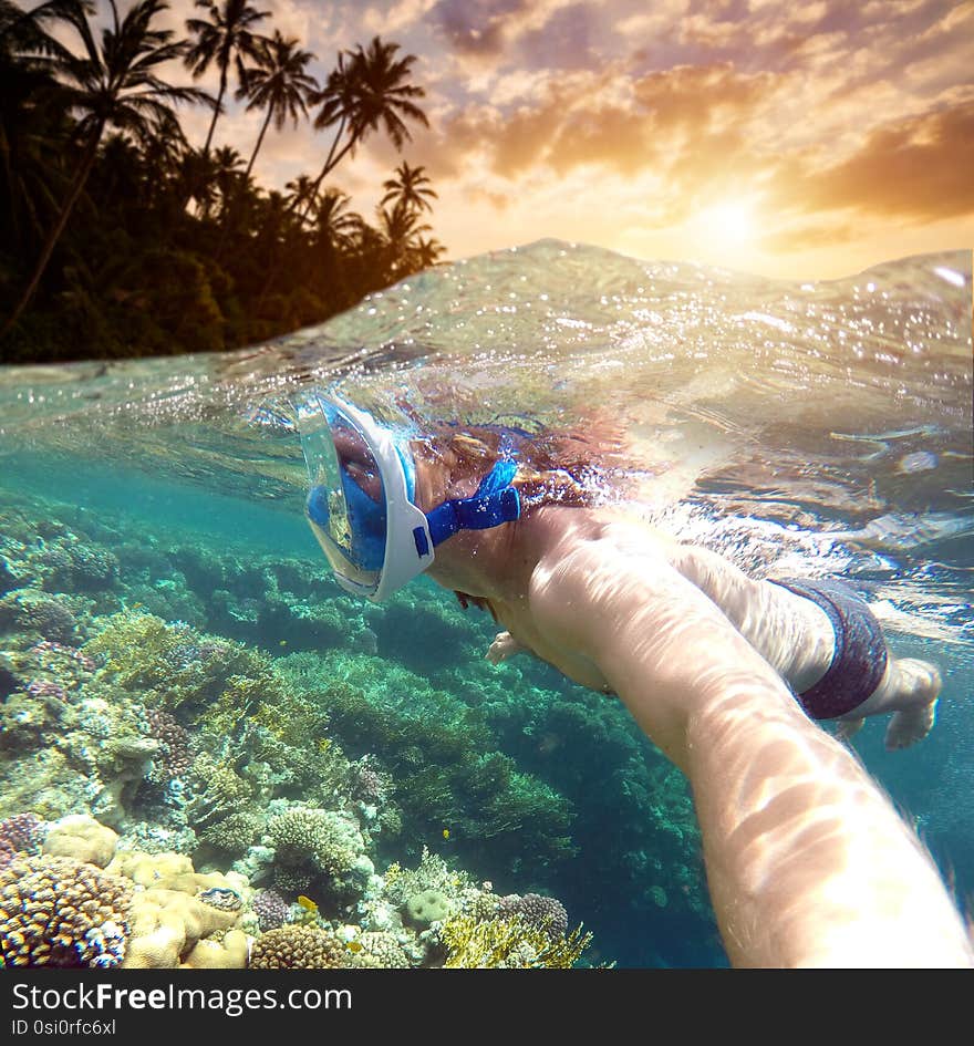 Snorkeling near a tropical island. Young man swims in the water. Sea vacation.