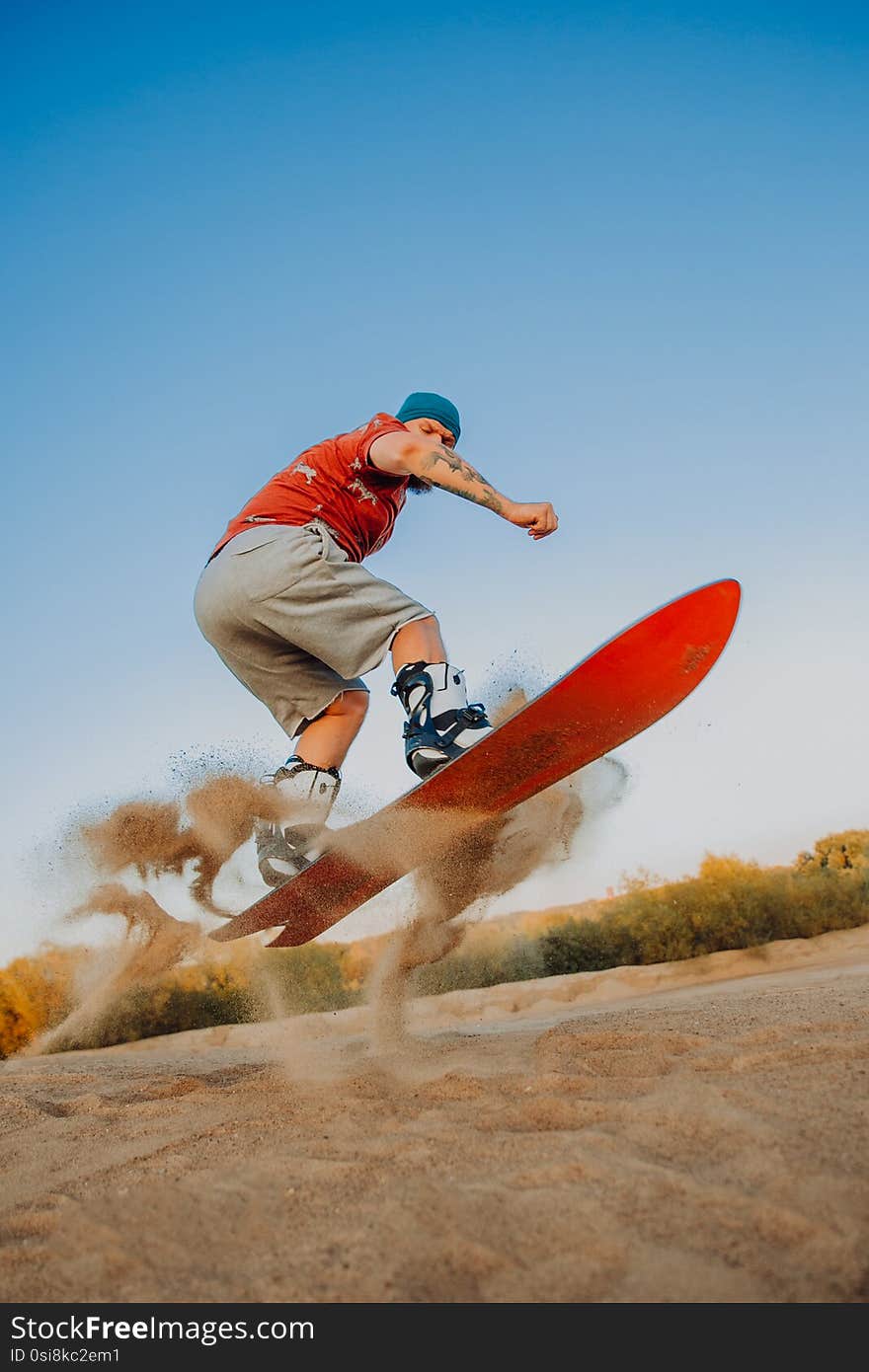 Tourist Sandboarding In the Desert Man jumps in and does the trick, outdoor