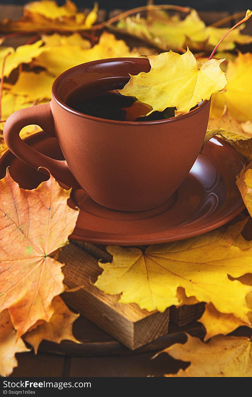Autumn, fall leaves, hot cup of coffee on wooden table background.