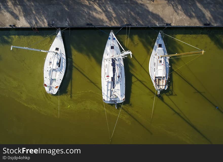 Pier with boats, marina lot. Aerial top view from drone. Green water due to seaweed