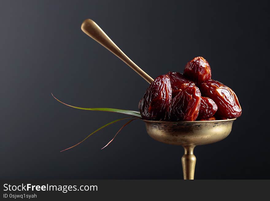 Closeup sweet dried dates in brass dish. Copy space