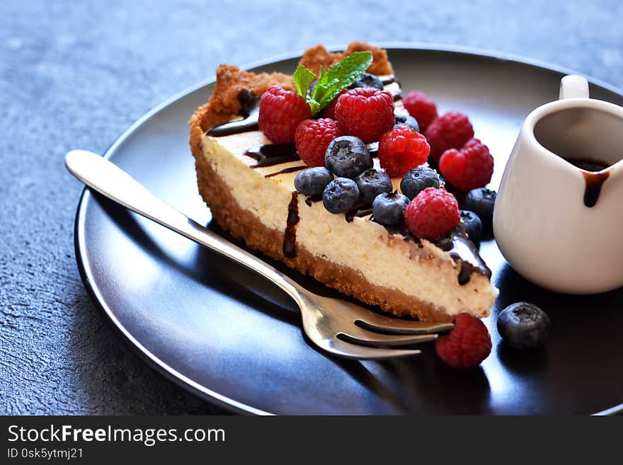 Homemade vanilla cheesecake with chocolate sauce and berries on a concrete background