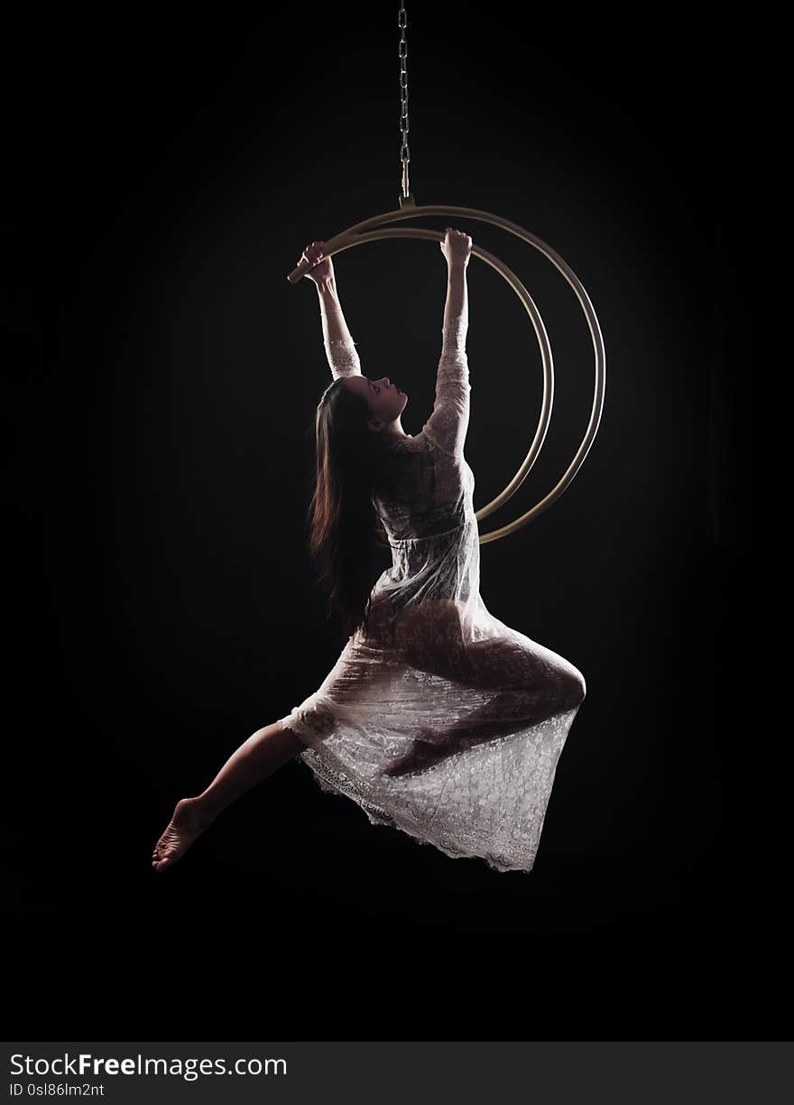 The girl, an aerial acrobat, performs on a sports equipment of the