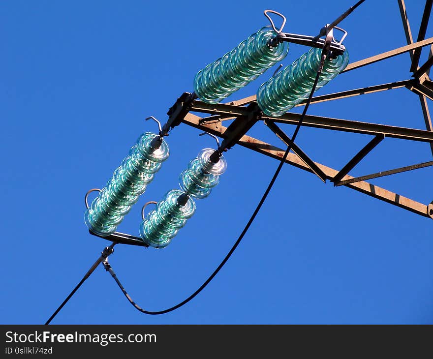 Glass disc electrical isolator plates in high voltage overhead electric wires. low level abstract view. blue sky above. electricity distribution concept. industries and technology. electricity utility