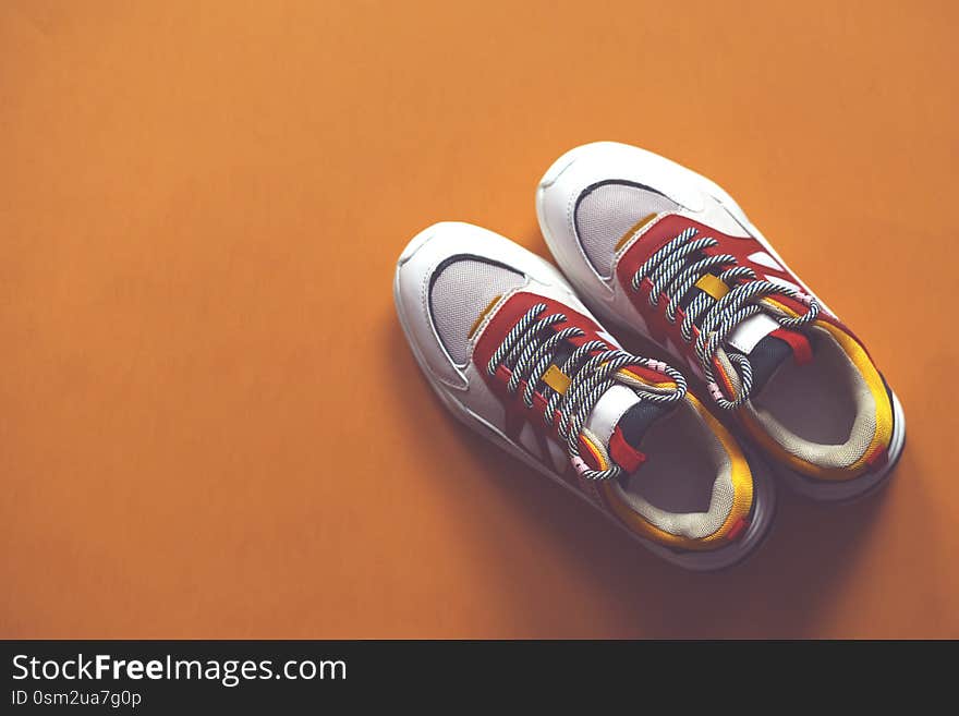 Multi-colored fashion sneakers on a orange background. Sport. There is a place for text