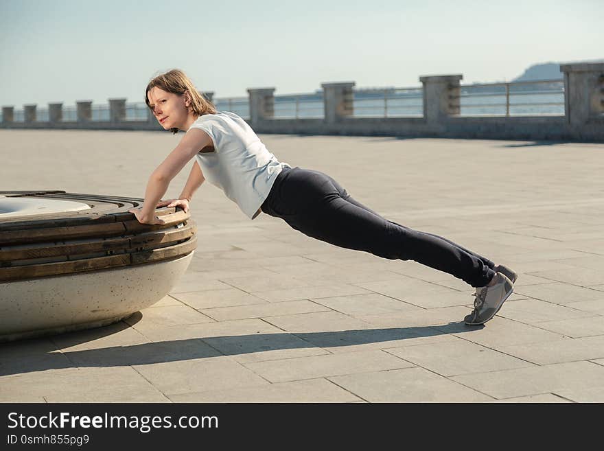 Young Woman Doing Sport Exercises Outside With Bench