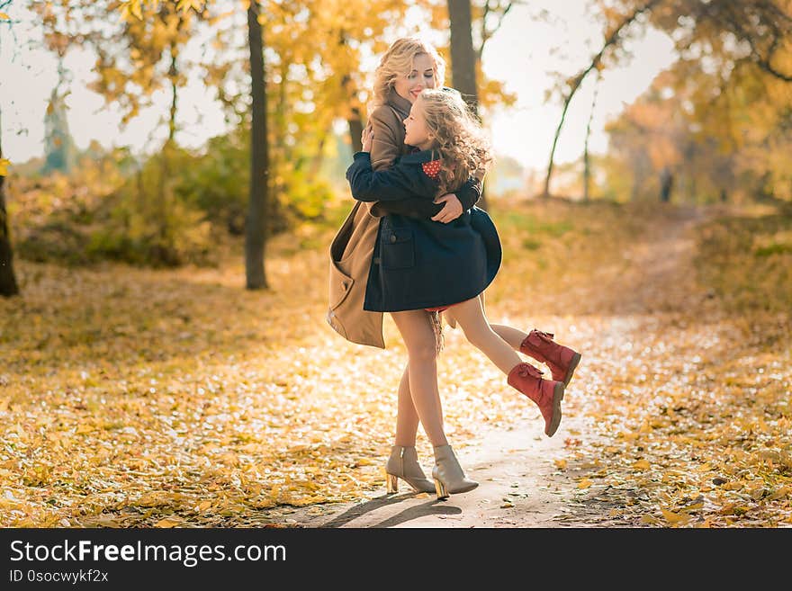 Young pretty mother with her little daughter having fun in the fall background. happy fami with child daughter pland laughing on autumn walk. Mother`s day. Young pretty mother with her little daughter having fun in the fall background. happy fami with child daughter pland laughing on autumn walk. Mother`s day