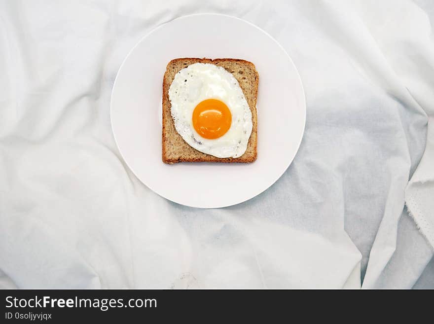 Toasted Bread With Fried Egg On The White Plate Fabric Background. Toasted Bread With Fried Egg On The White Plate Fabric Background