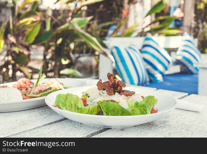 Caesar Salad on a white wooden table in the beach cafe, Bali island. Indonesia.