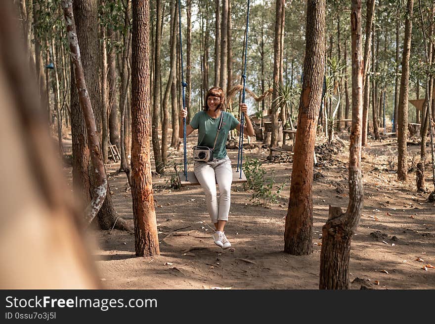 Young woman on the swing in the forest. Bali island. Indonesia.