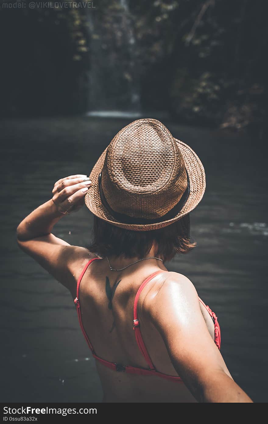 Rear view of young woman tourist with straw hat and red swimsuit in the deep jungle. Real adventure concept. Bali island. Indonesia.