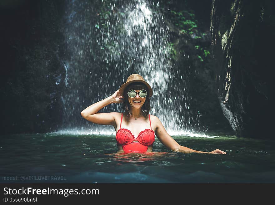 Young woman tourist in the deep jungle with waterfall. Real adventure concept. Bali island. Indonesia.