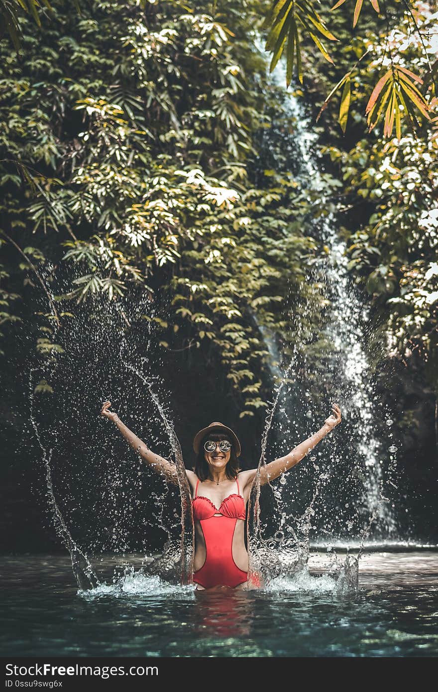 Young woman tourist in the deep jungle with waterfall. Real adventure concept. Bali island. Indonesia. Young woman tourist in the deep jungle with waterfall. Real adventure concept. Bali island. Indonesia.