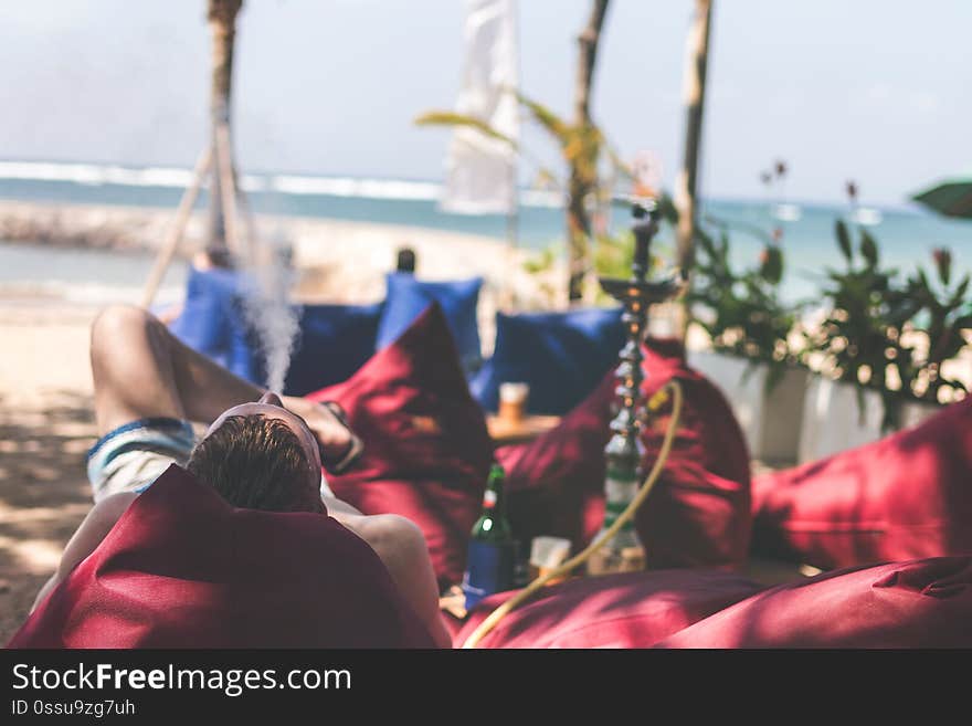 Man smoking hookah on a beach side restaurant next to the sea. Shisha smoking. Bali island. Indonesia.